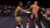 two wrestlers are fighting in front of a crowd with a com logo