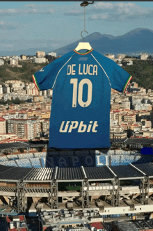 a blue jersey with the name de luca on it hangs from a hanger