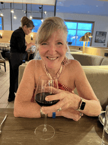 a woman sitting at a table with a glass of wine