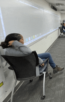 a woman sits in a chair in front of a whiteboard that says ' i 'm tired ' on it