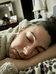 a woman is sleeping in a bed with her eyes closed