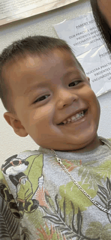 a young boy is smiling in front of a sign that says " parent notice "