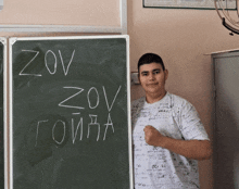 a young man stands in front of a blackboard that says zov