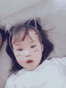 a little girl wearing a cat ear headband has stickers on her face