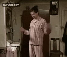 mr bean is wearing pajamas and dancing in a room .