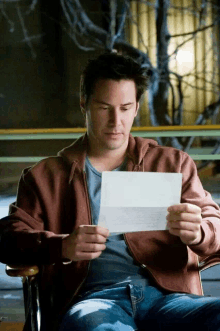 a man in a brown jacket is holding a piece of paper with a letter on it