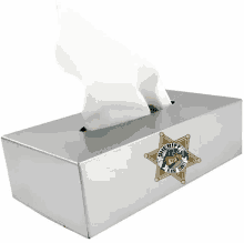 a stainless steel tissue box with a sheriff 's badge on it is filled with tissues .