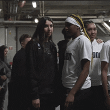 a group of people are standing in a dark room and one of them is wearing a white shirt with the word oni on it