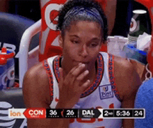 a female basketball player is sitting in the stands during a game with the score 36-26