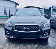 a grey infiniti car is parked in a parking lot