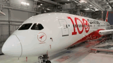 a white and red airplane is parked in a hanger .