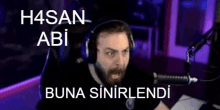 a man wearing headphones is sitting in front of a microphone with the words h4san abi buna sinirlendi on the bottom