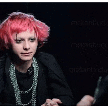 a young man with pink hair is wearing a black shirt and a necklace .