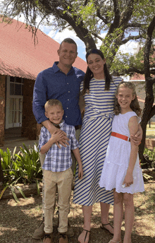 a family poses for a picture in front of a red roofed building