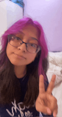 a girl with purple hair and glasses giving the peace sign