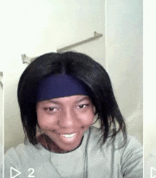 a woman wearing a blue headband is smiling and taking a selfie