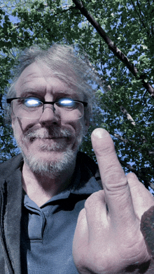 a man wearing glasses and a blue shirt giving the middle finger