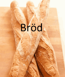 three loaves of bread are on a wooden cutting board with the word bröd written above them