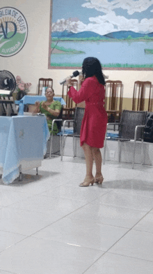 a woman in a red dress sings into a microphone in front of a sign that says " iglesia de deus "