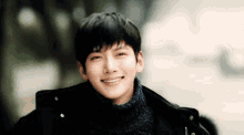 a young man wearing a sweater and a jacket is smiling .