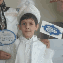 a young boy wearing a turban and holding a sign is standing next to a woman .