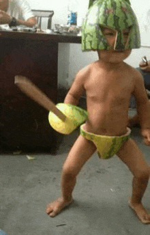 a young boy wearing a watermelon helmet and holding a sword .