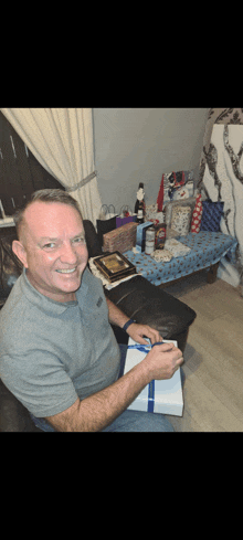 a man is sitting on a couch holding a gift box