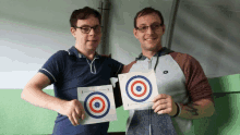 two men are holding up a target that says ' i ' on it