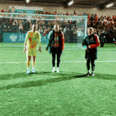 three soccer players stand on a field in front of a sign that says the fisher & borkhamwood town council