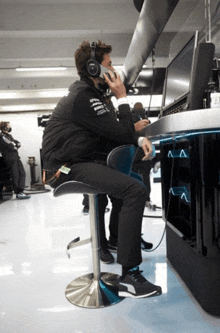 a man wearing headphones is sitting on a bar stool in front of a monitor