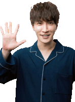 a young man wearing a blue pajama shirt waves his hand in front of a white background