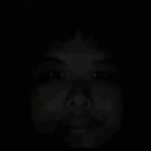 a close up of a person 's face in the dark with their eyes visible