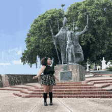 a woman stands in front of a statue with a plaque on it that says ' a ' on it