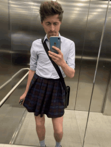 a man in a plaid skirt is taking a selfie with his phone