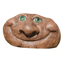 a statue of a rock with a face and green eyes