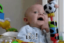 a baby is playing with a soccer ball while holding a stack of blocks with a soccer ball on top of them