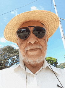 an older man wearing a straw hat and sunglasses looks at the camera