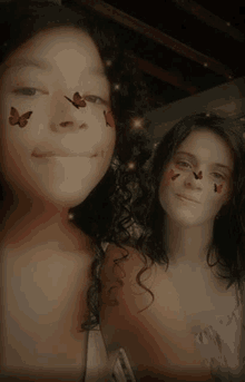 two girls with butterflies painted on their faces are posing for a picture .