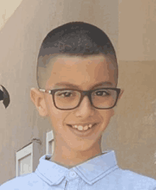 a young boy wearing glasses and a blue shirt is smiling for a picture .