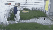 a man and a woman are kissing in front of a white fence with a sign that says real time