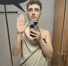 a young man wrapped in a towel is taking a picture of himself