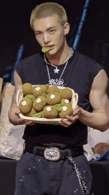 a man is holding a basket of kiwi fruit with a green leaf on it