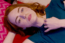 a woman with red hair is laying on a bed