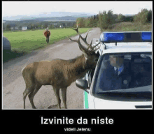 a picture of a deer standing in front of a police car with the caption izvinite da niste