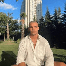 a man in a white shirt is sitting in front of a tall building .