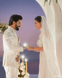 a man in a white suit and a woman in a white dress holding hands