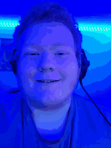 a man wearing headphones is smiling in front of a blue wall