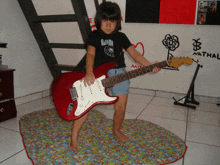 a little girl is holding a red guitar and wearing a black shirt that says " amor "