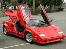 a red sports car with its hood open is parked in a parking lot .