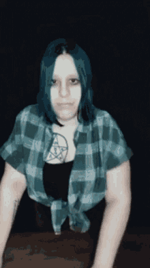 a woman with blue hair has a pentagram tattoo on her chest .